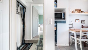A hallway with a door, a bench, and a microwave on a shelf.