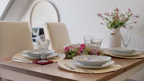 A dining table set with plates, glasses, and a vase of flowers.