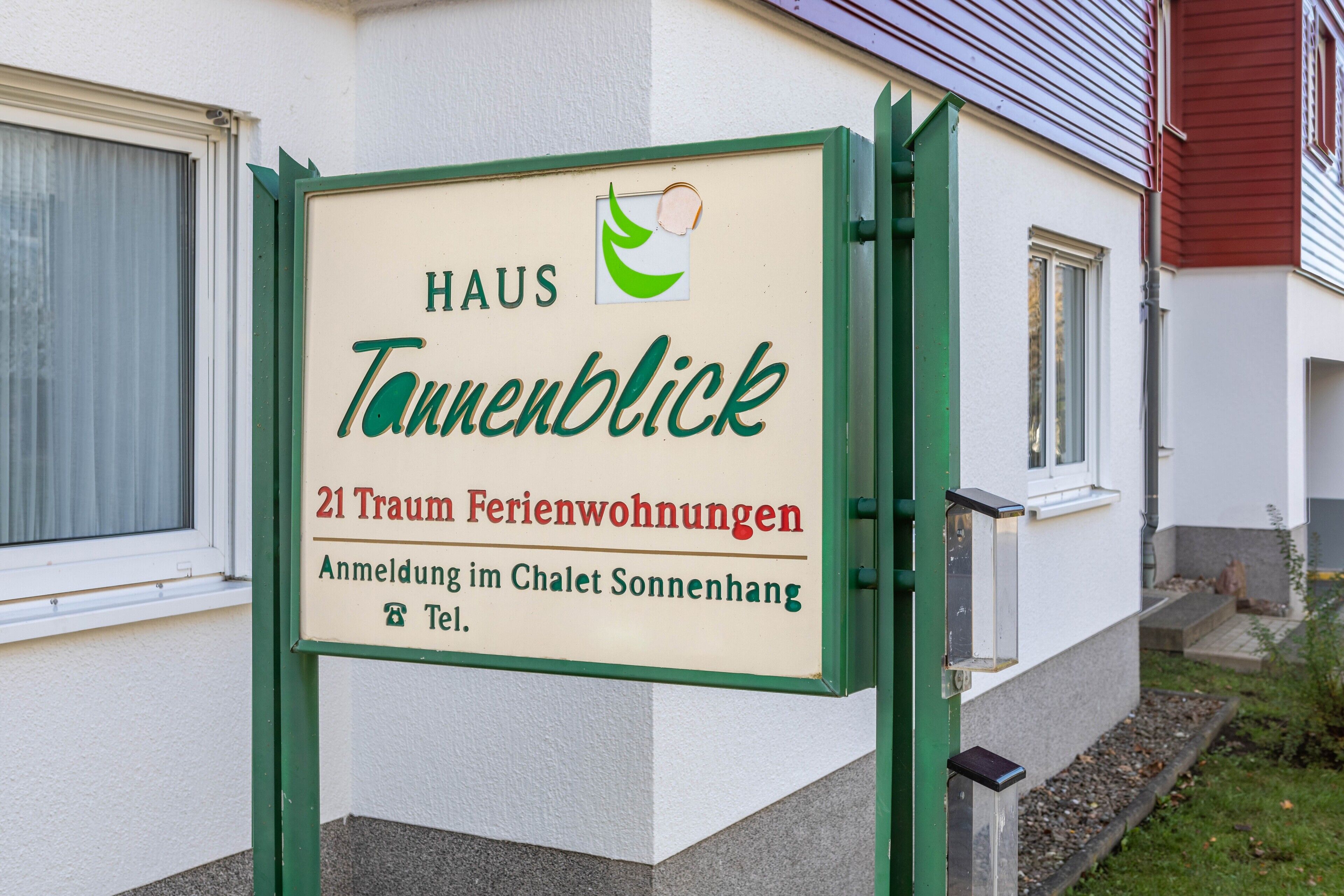 Señal de un hotel llamado 'Haus Tannenblick' con 21 alojamientos turísticos, ubicado en Chalets Sonnenhang, Tel.