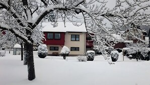 A two-story building with a red facade, multiple windows, and snow-covered surroundings.