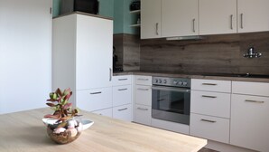 A modern kitchen with white cabinets, a wooden countertop, and a built-in oven.