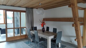Et spiseområde med et træbord, stole og en vase med blomster.