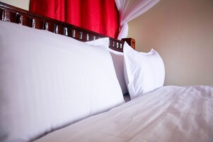 Una cama con sábanas blancas y un cabecero de madera.