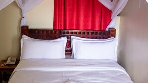 A bed with white linens, a red bedspread, and a white towel. - Turbine Ngong Hotel (Ngong)