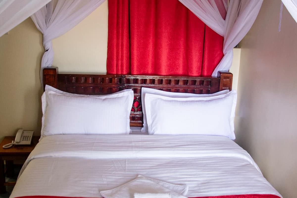Ein Bett mit weißen Laken, einer roten Decke und einem weißen Handtuch.