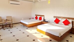 Ein Hotelzimmer mit zwei Betten, einem Sessel, einem Tisch und einer Klimaanlage.