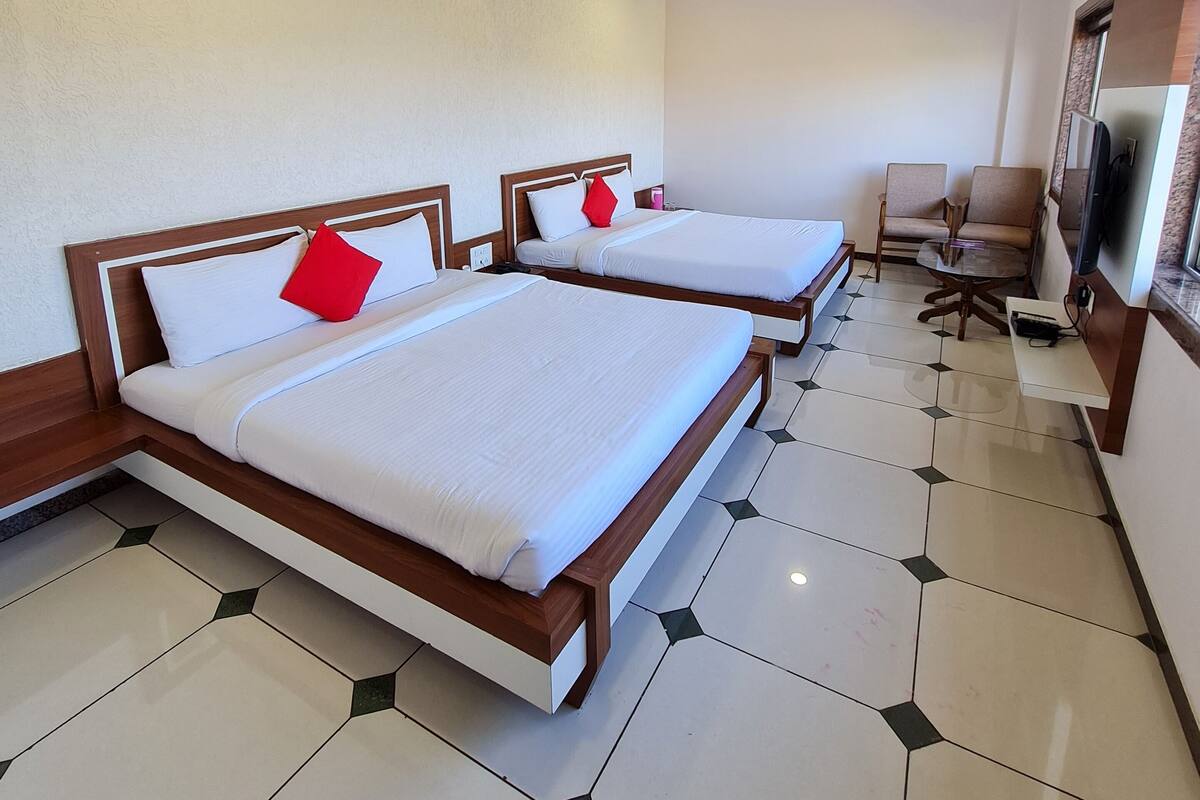 A hotel room with two beds, a ceiling fan, and a TV.
