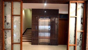 An interior with a central elevator, a staircase, and decorative glass panels with floral designs. - HOTEL SHIV SHAKTI (Goharganj)