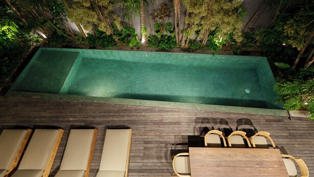 Piscina al aire libre con sillones de descanso y terraza de madera.