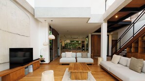 Una sala de estar moderna con televisor de pantalla plana, sofás, una mesa de centro y una escalera.