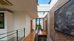 A modern interior with a skylight, wooden flooring, a blackboard with equations, and a glass railing. - Villa Pakuk by Alfred in Bali (Canggu)