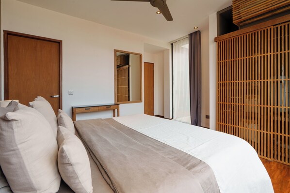 A bedroom with a bed, a wooden wardrobe, a mirror, and a ceiling fan. - Villa Pakuk by Alfred in Bali (Canggu)
