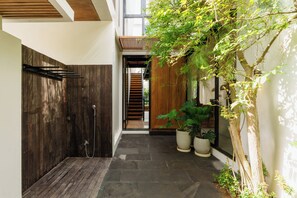 A narrow corridor with a wooden wall, a metal rack, and a potted plant.