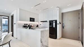 Una cocina moderna con armarios blancos, un refrigerador negro y una isla de mármol.