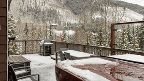 A snow-covered deck with outdoor seating and a hot tub, overlooking a mountainous landscape. - Cascade Village - Westhaven Condo Sleeps 24 (Vail)