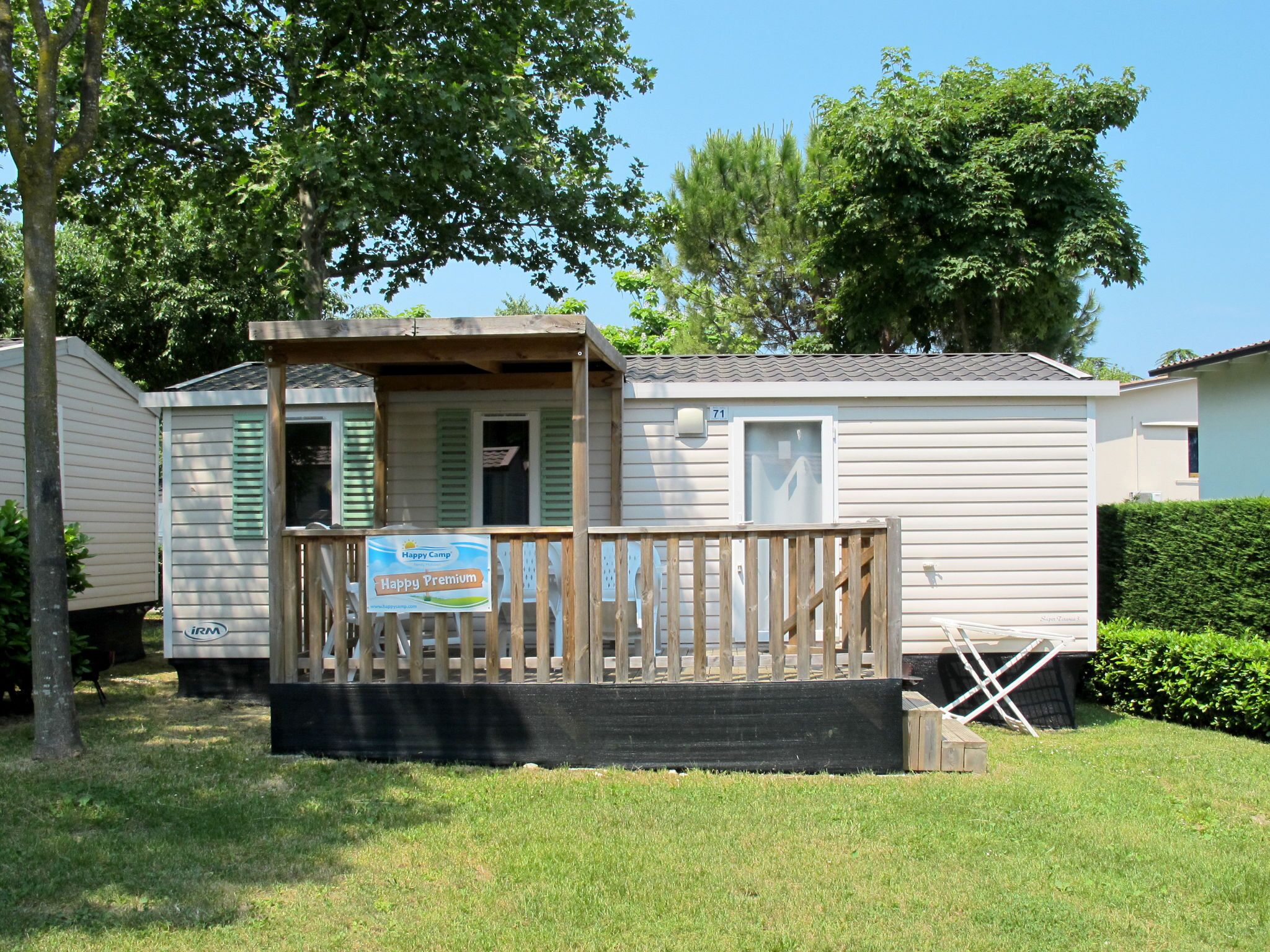 Une maison mobile dotée d’une terrasse en bois et d’une enseigne indiquant « Happy Camp ».