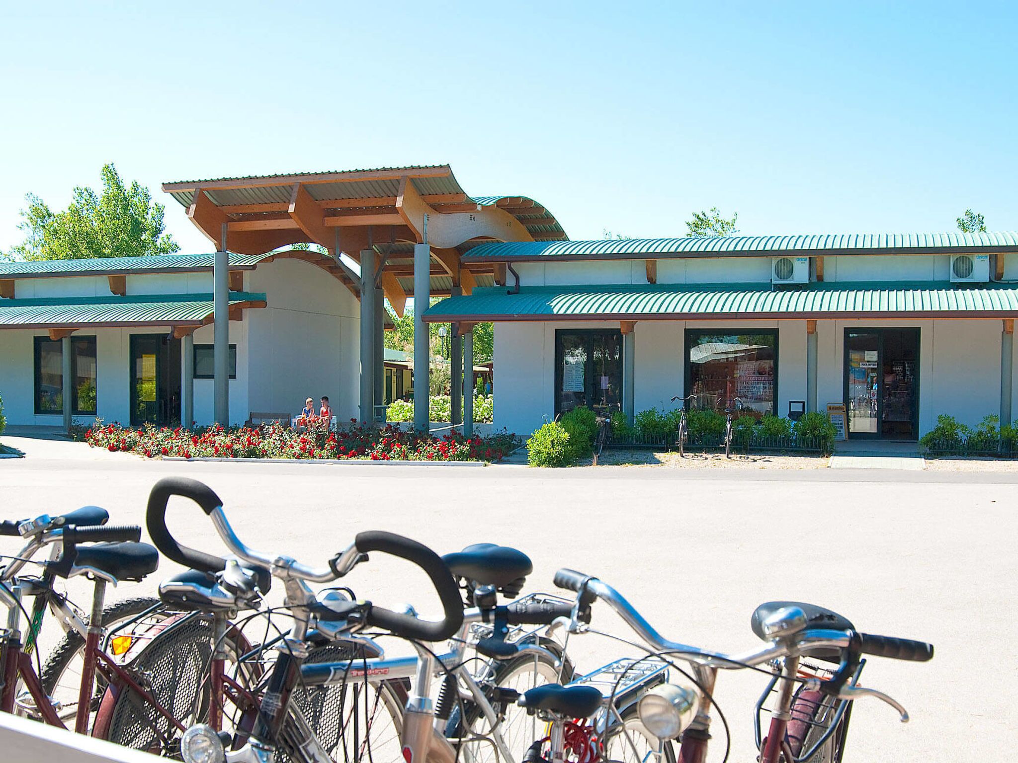 A building with a covered entrance and a row of bicycles parked in front.
