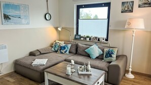 Ein modernes Wohnzimmer mit Ecksofa, Couchtisch, Lampe und Kunstwerken an den Wänden.