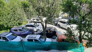 A parking lot with multiple cars and a green fence. - Apple Field House - Hotel in Old Manali (Manali)