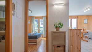 A modern room with a bed, a wooden cabinet, a wicker basket, and a potted plant. - Seya 15 by Interhome (Ovronnaz)