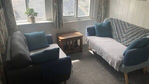 A cozy living room with a sofa, armchair, and a small wooden table. - Dinham Cottage - Cornish Cottage in Boscastle Harbour (Boscastle)