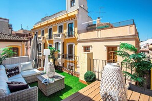Un cortile con un divano, mobili in vimini e un tavolino.