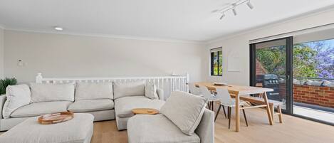 Een moderne woonkamer met een modulaire bank, een eettafel en uitzicht op het buitenleven.