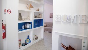 Moderni olohuone, jossa on valkoiset seinät, sininen hyllykkö ja koristeena sana «HOME».