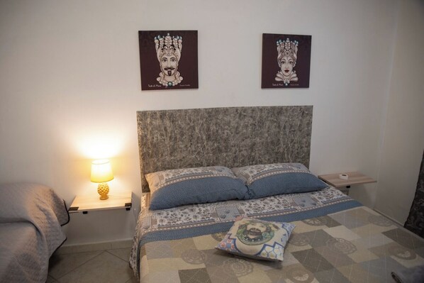 Ein Schlafzimmer mit einem großen Bett, zwei Nachttischen, einem Beistelltisch und einer Wandlampe.