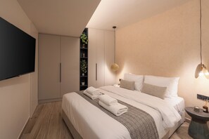 Ein modernes Schlafzimmer mit einem großen Bett, einem Flachbildfernseher, einem Nachttisch mit Lampe und einer eingebauten Regalanlage mit Pflanzen.