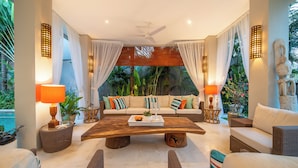 A modern living room with a sofa set, a coffee table, wicker chairs, and ambient lighting. - Villa Sunsara 2 (Canggu)