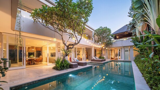 A modern poolside area with a clear pool, outdoor seating, and lush greenery. - Villa Sunsara 2 (Canggu)