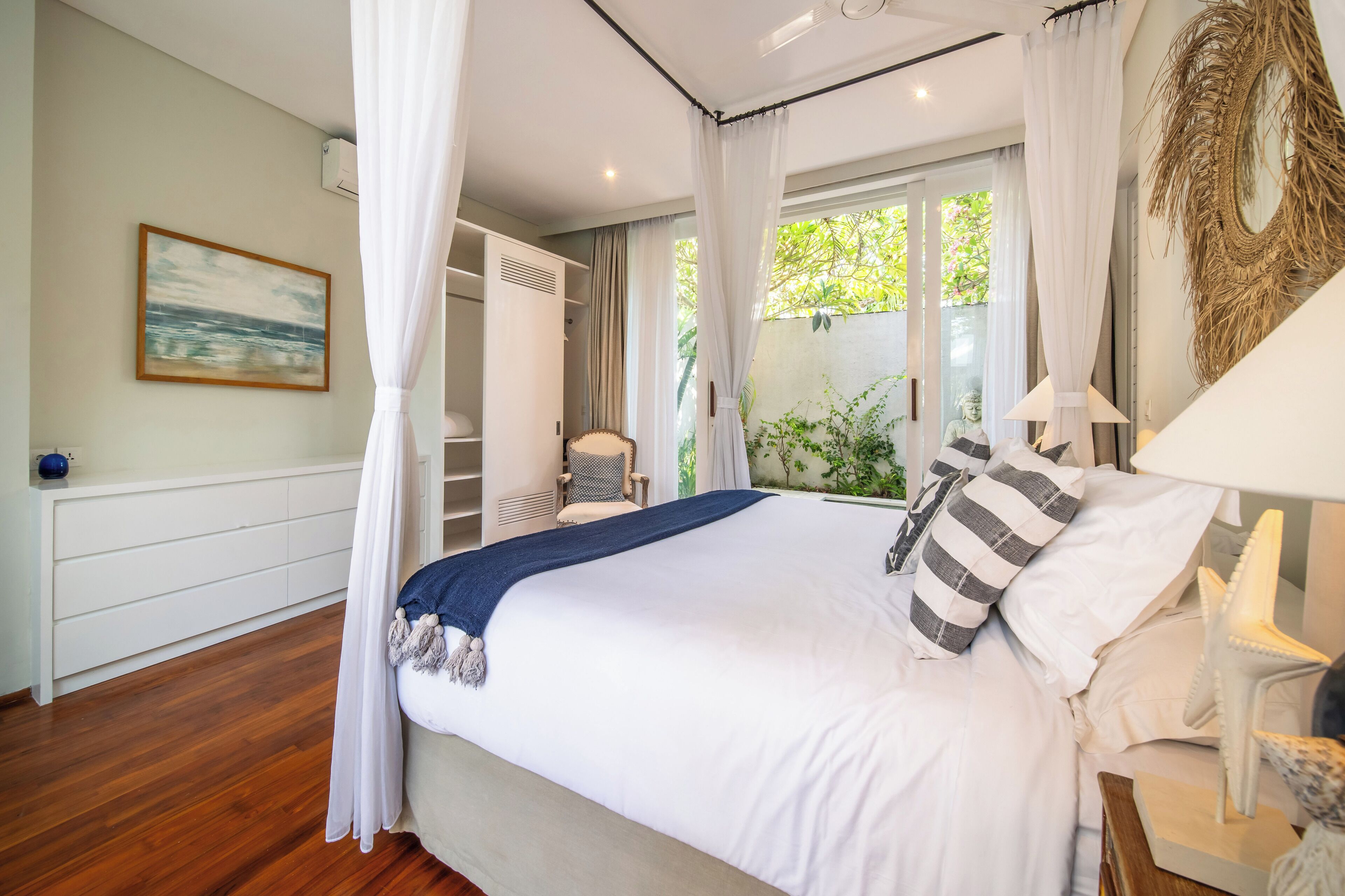 A bedroom with a large bed, a nightstand, a chair, a wardrobe, and a painting on the wall.