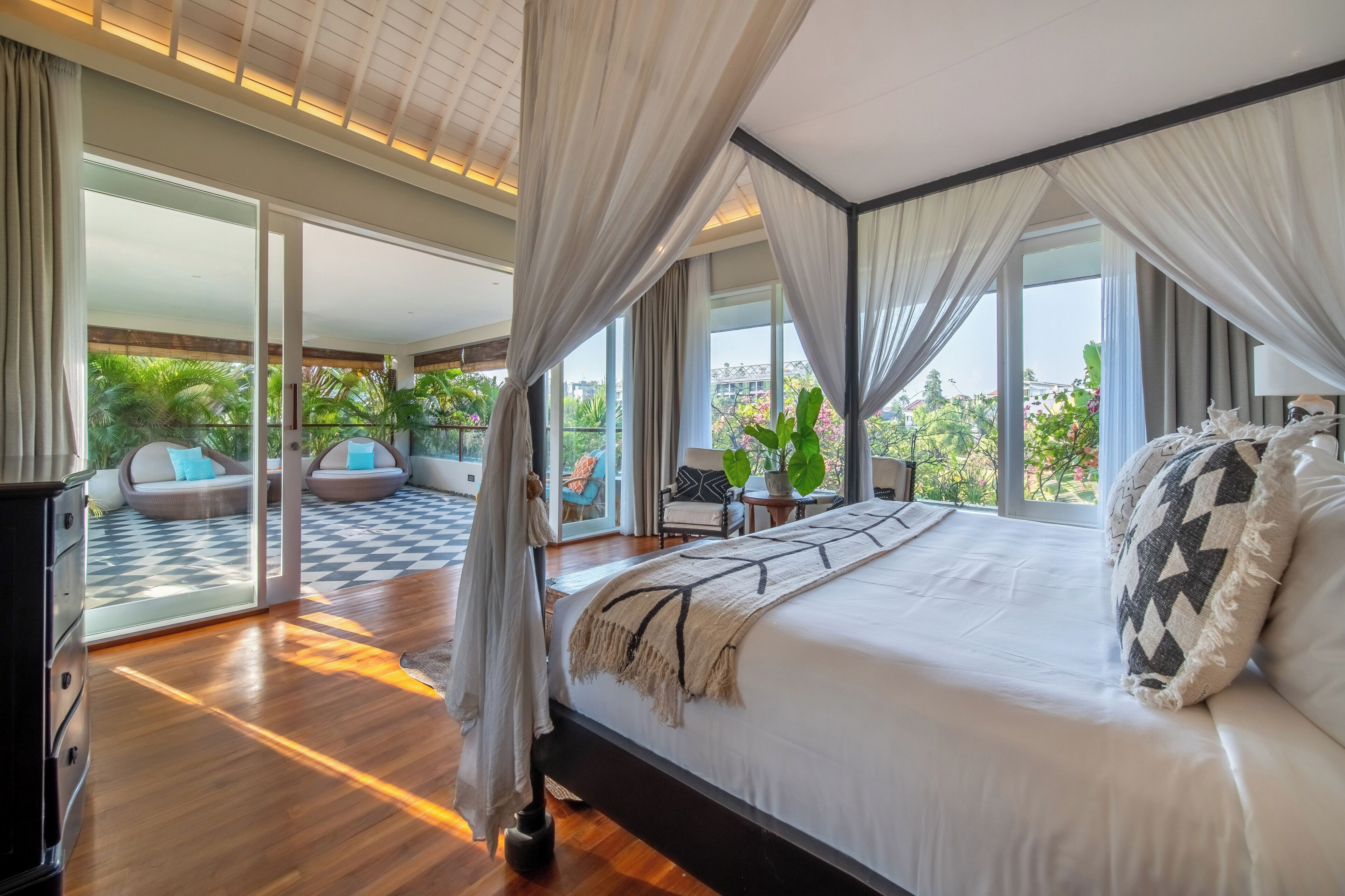 Un dormitorio con una cama grande, vistas al exterior y un balcón con mobiliario.