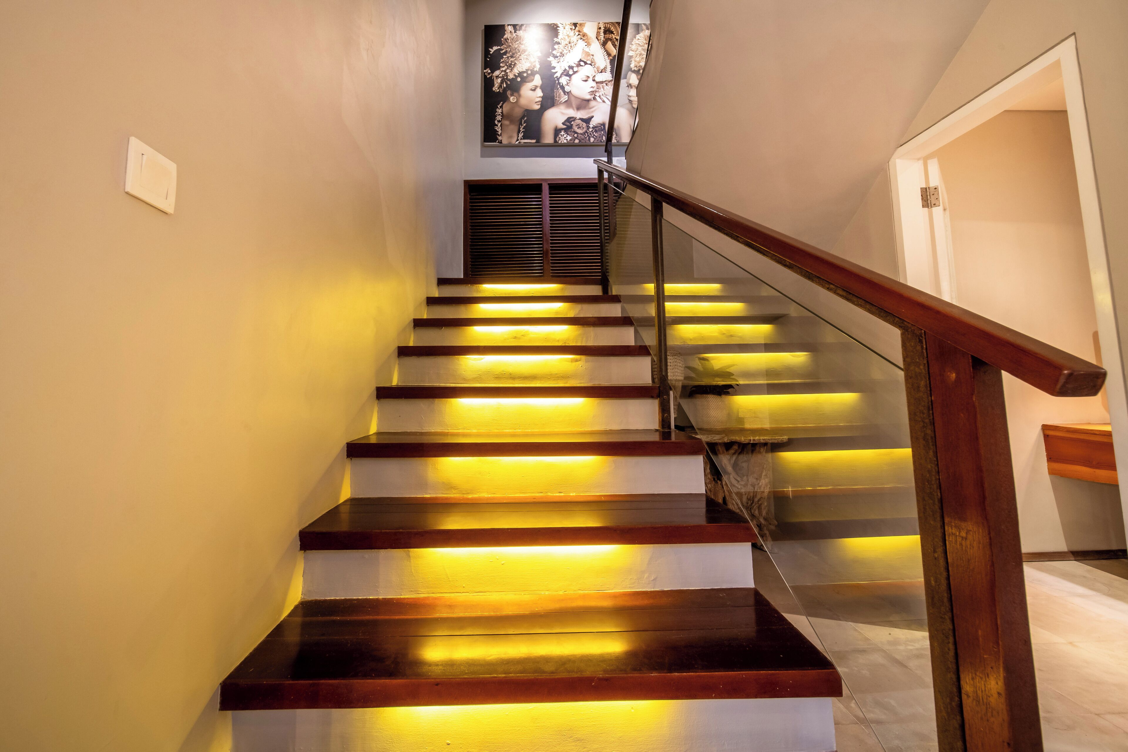 Eine Treppe mit Holzsitzen und Glastrennwand, beleuchtet durch integrierte Beleuchtung.