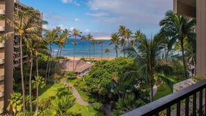Ein Hotelbalkon mit Blick auf einen Strand, Palmen und einen klaren Himmel.