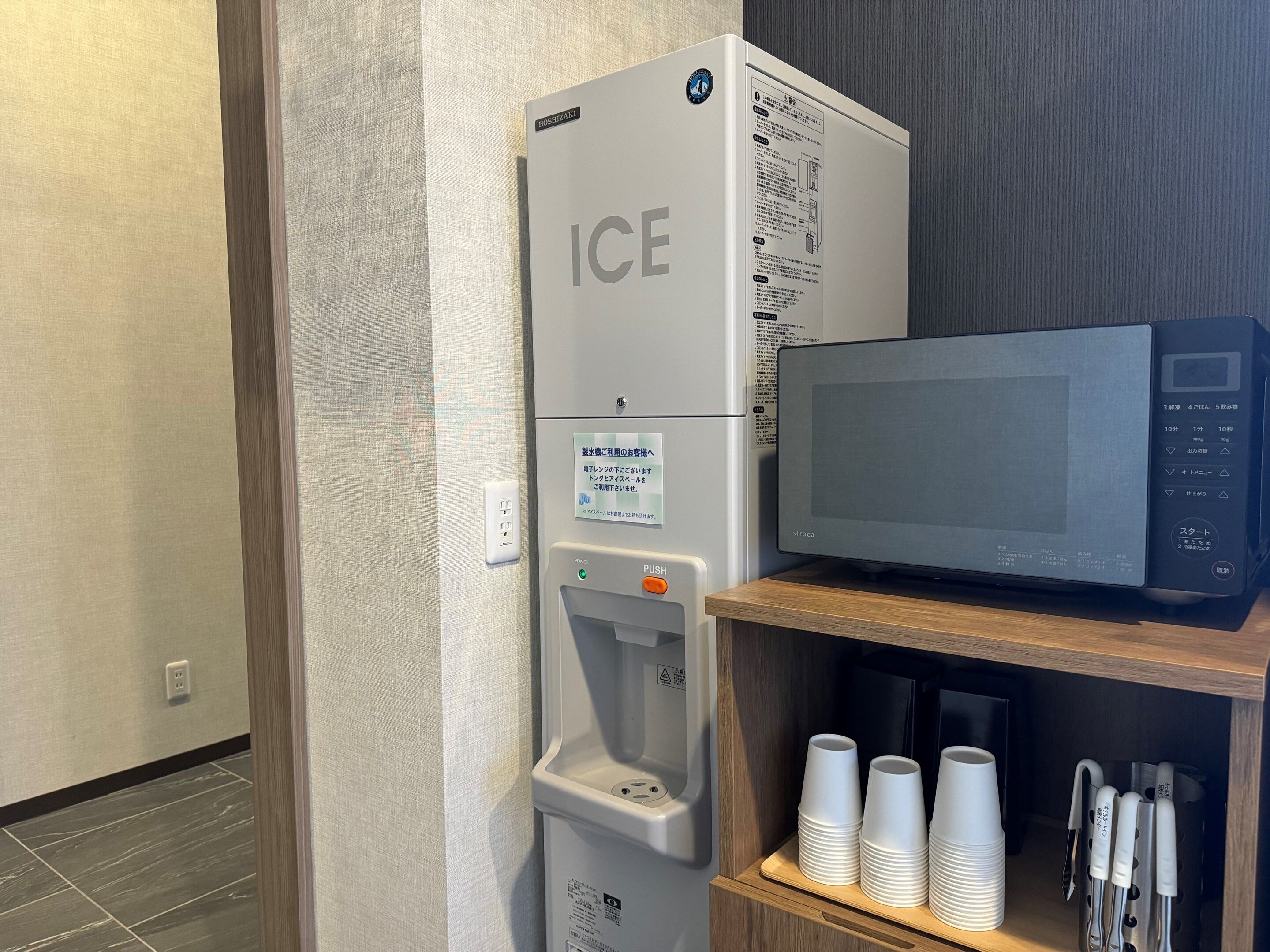 Ein Kühlschrank mit Eisbereiter und eine Mikrowelle auf einer Holzablage.