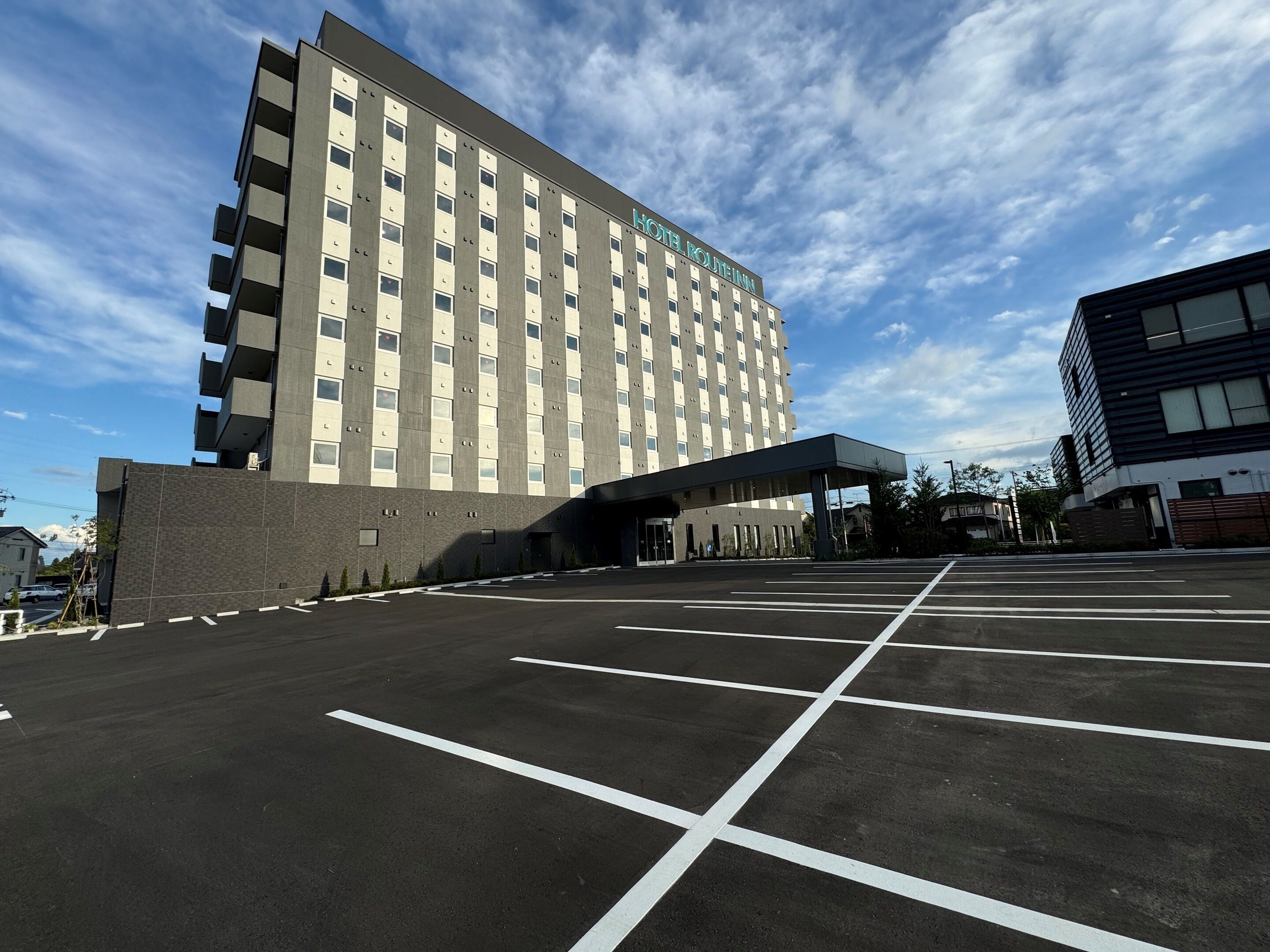 A hotel with a modern design, featuring a large parking lot in front.