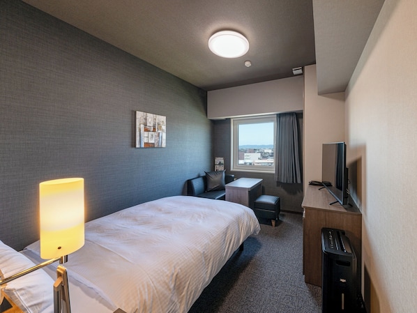 A hotel room with a bed, a desk, a chair, a TV, and a window with a view. - Hotel Route Inn Tonami Inter (Tonami)