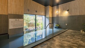 A modern indoor pool area with a glass barrier, wooden panel walls, and a tiled floor. - Hotel Route Inn Tonami Inter (Tonami)