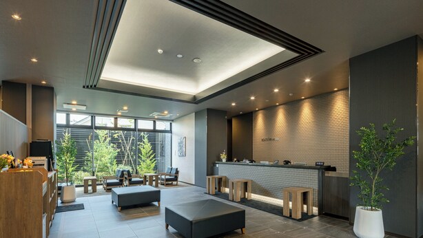 A modern hotel lobby with a reception desk, seating area, and large windows offering a view of greenery. - Hotel Route Inn Tonami Inter (Tonami)