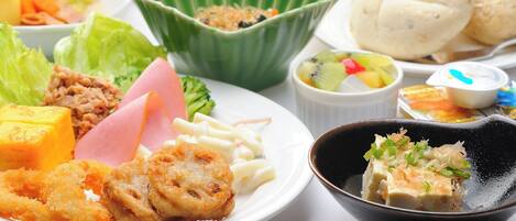 A table with various dishes including fried items, a bowl of salad, and a glass of orange juice.