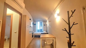 A narrow hallway with a bed at the end, a table with chairs, and a coat rack. - Cozy apartment for families and groups of friends 5 minutes from downtown (Torino)