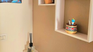 A wall with built-in shelves holding various items including a framed picture, a potted plant, and a decorative bowl. - Cozy apartment for families and groups of friends 5 minutes from downtown (Torino)