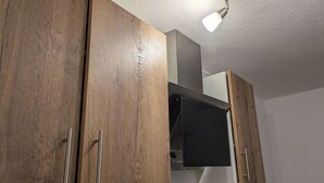 Una cocina con armarios de madera, una campana extractora negra y una pared blanca.