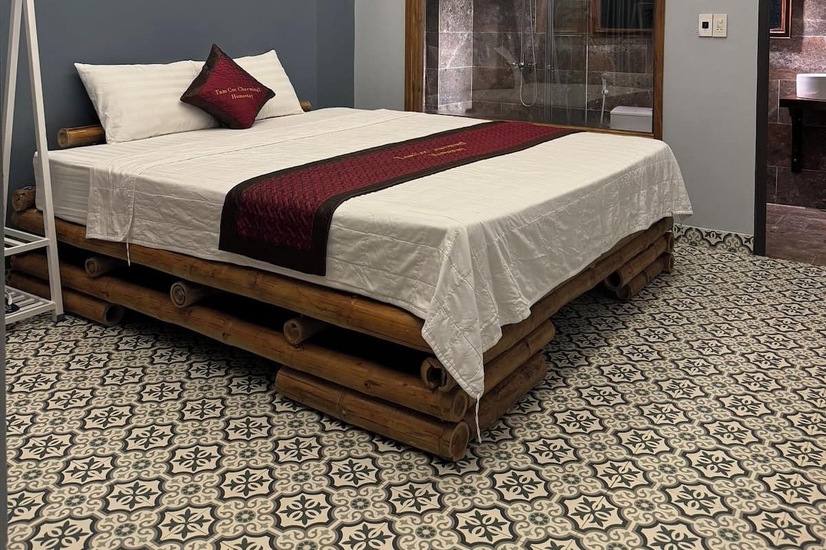 Ein Schlafzimmer mit einem Bett, einem Holzkopfstück, einem gemusterten Boden und einer Deckenleuchte.