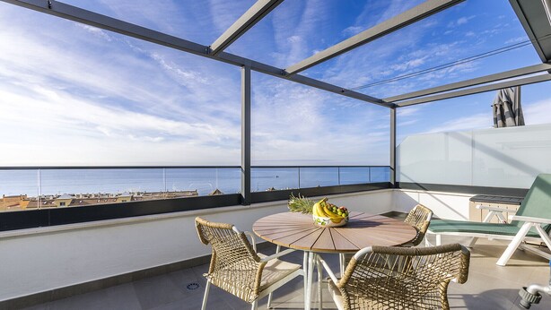A balcony with a round table, wicker chairs, and a view of the sea. - A&N atico dimo terraza del Mar (Algarrobo Costa)