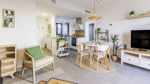 A modern living room with a dining area, kitchen, and a TV on a wooden stand. - A&N atico dimo terraza del Mar (Algarrobo Costa)