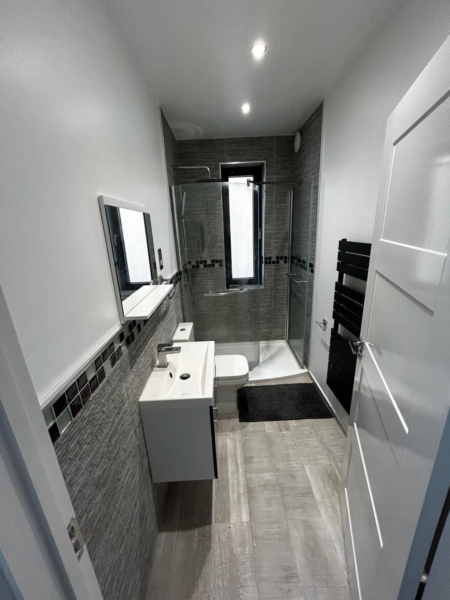 A modern bathroom with a shower, toilet, and sink.