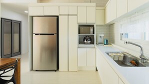 A modern kitchen with a stainless steel refrigerator, a built-in coffee maker, and a sink with a faucet. - Jeju Pureunbada Pet Dokchae Pension (Jeju City)